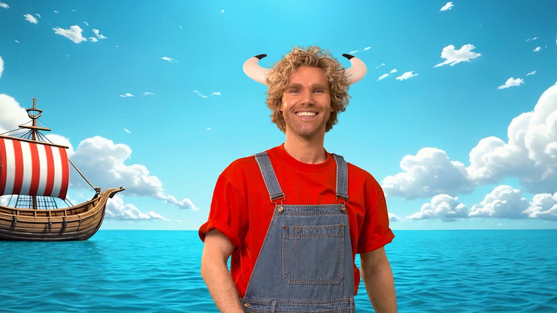 Matt lächelt in rotem Shirt und Latzhose vor einer fantasievollen Meereskulisse